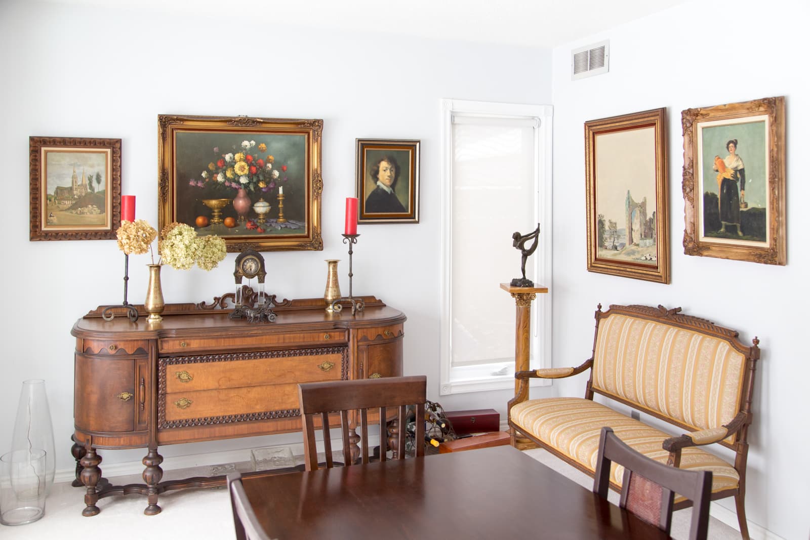 The dining room — an antique walnut sideboard, framed oil paintings and a striped settee