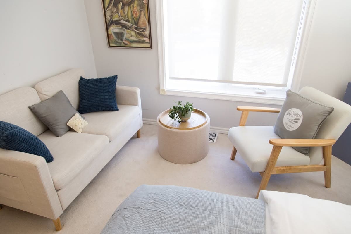 The sitting corner of the Blue Room — a pale sofa, a wooden-armed chair and a round ottoman