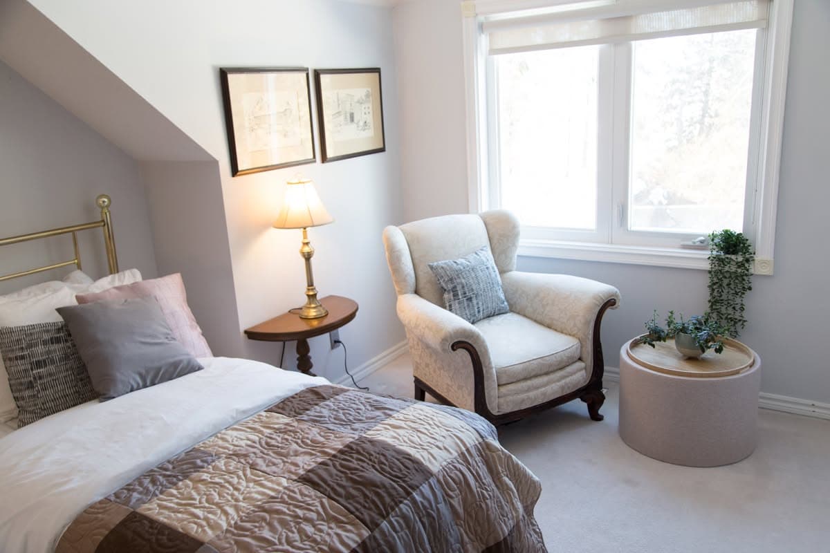 The reading corner of the Brass Room — a wingback chair, brass lamp and framed sketches