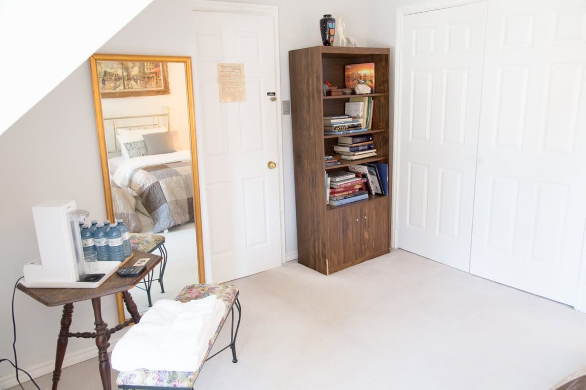 The entry side of the Brass Room, with a full-length mirror, bookcase and coffee station