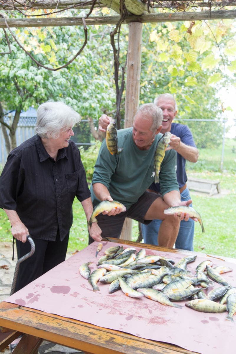 Family laughing together over the day’s catch of perch on the pergola picnic table